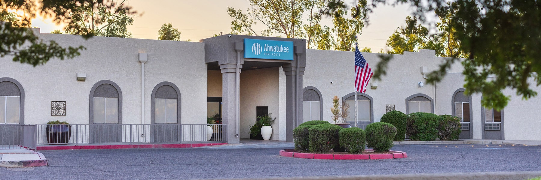 Front driveway view of building and flag at Ahwatukee Post Acute